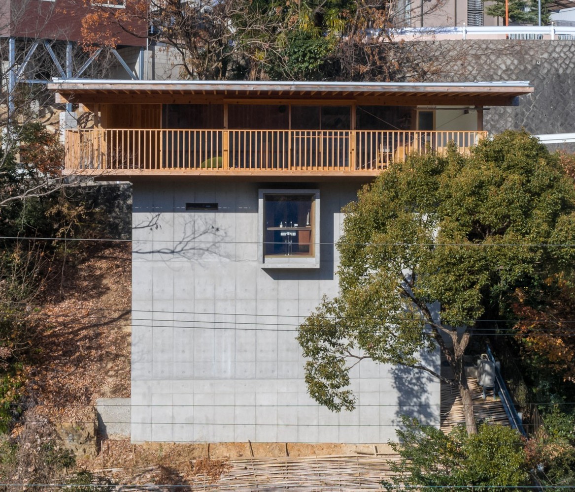 Hình ảnh toàn cảnh mặt tiền ngôi nhà 3 tầng ở Nhật với tầng thứ 3 làm bằng gỗ, xung quanh có nhiều cây cối
