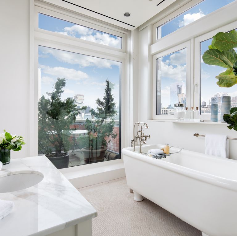 Hình ảnh phòng tắm thoáng sáng với bồn rửa, bồn tắm bằng sứ trắng, cửa kính cao rộng