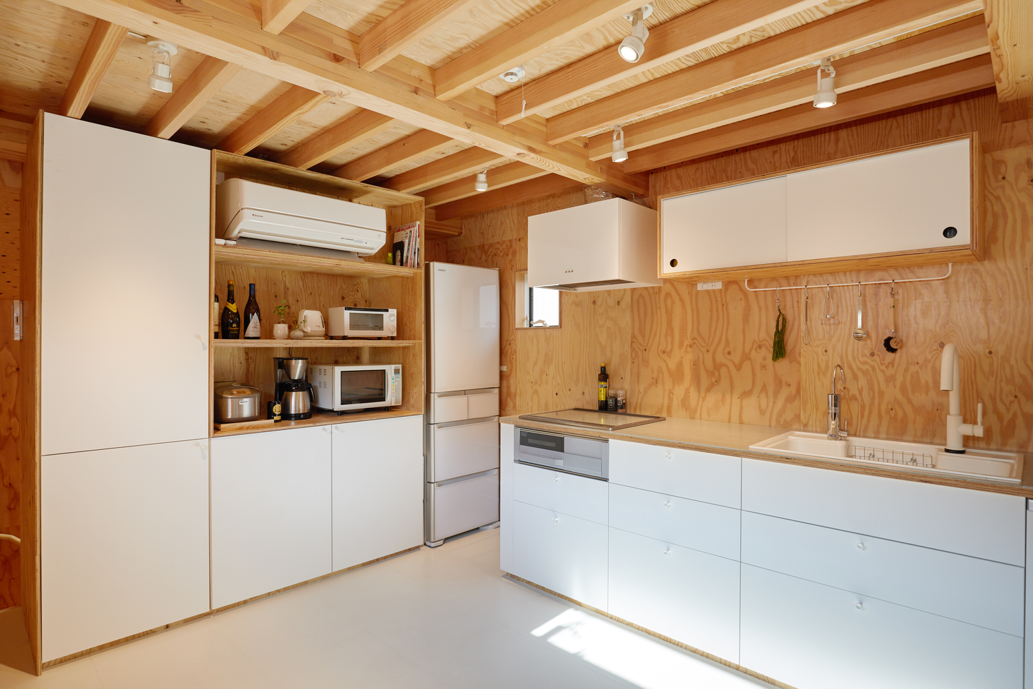 Hình ảnh phòng bếp với hệ tủ màu trắng, trần lộ dầm gỗ