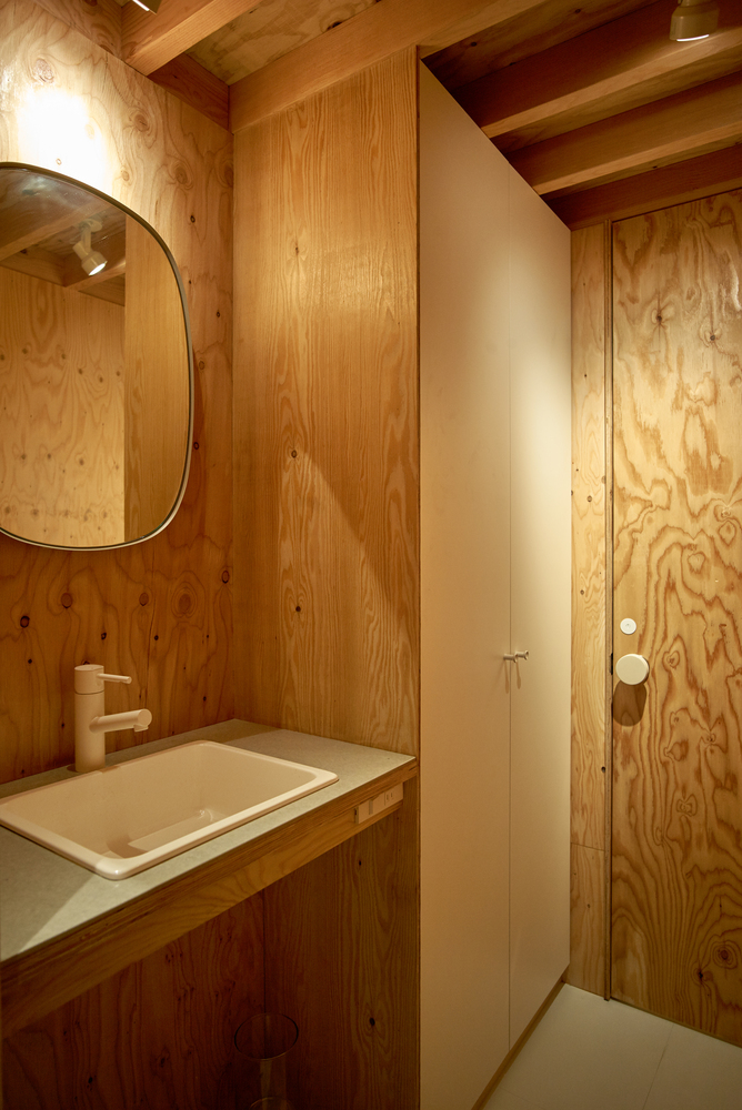 Hình ảnh bên trong phòng vệ sinh nhà thùng sữa với trần và tường ốp gỗ, gương soi gắn tường