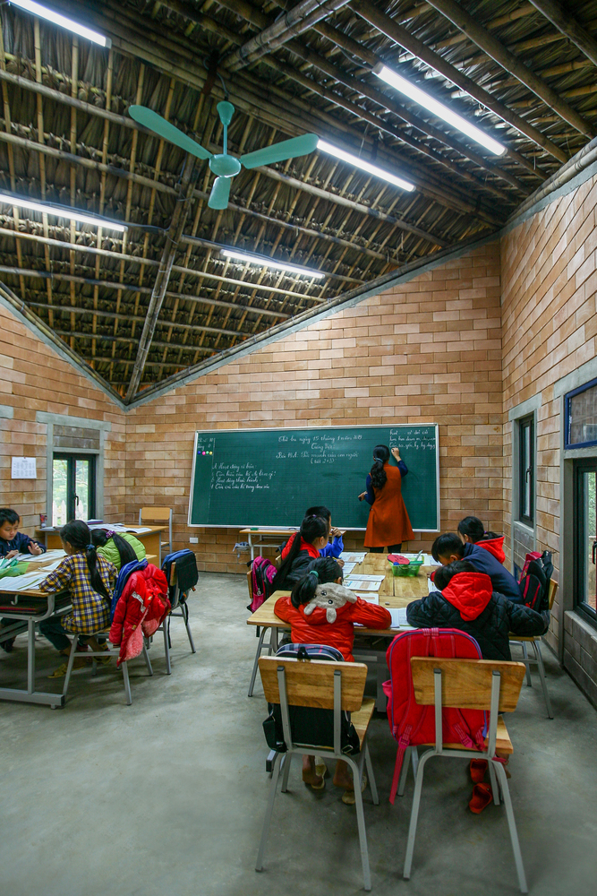Hình ảnh cô giáo đang dạy các em học sinh trong ngôi trường mái lá độc đáo