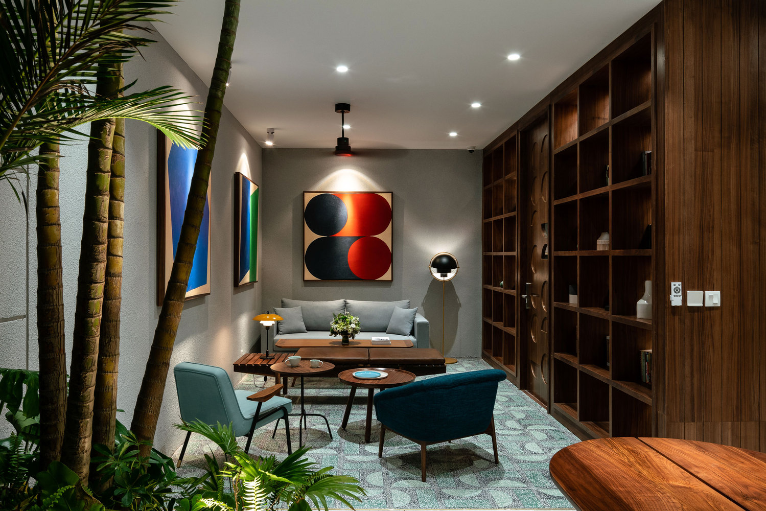 Hình ảnh phòng khách căn hộ dịch vụ với hệ tủ gỗ lớn, tranh treo tường nghệ thuật, cây xanh trang trí