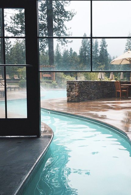 Hình ảnh một góc bể bơi được thiết kế từ trong nhà ra ngoài trời với tường kính ngăn cách ở giữa