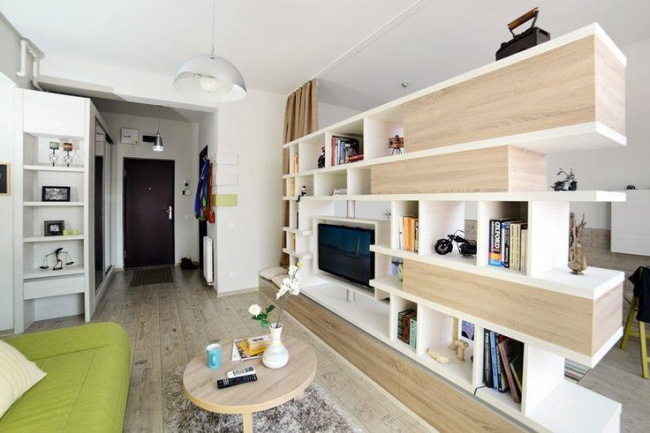 Hình ảnh phòng khách căn hộ nhỏ sofa màu xanh lá, bàn trà tròn, kệ tivi tích hợp lưu trữ
