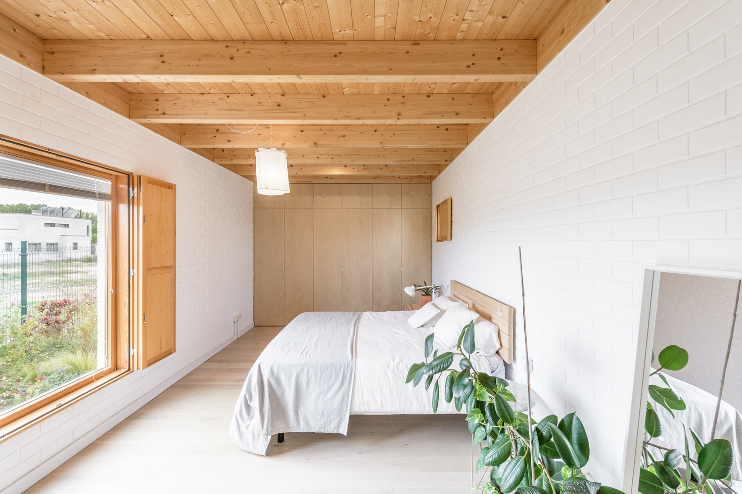 Hình ảnh toàn cảnh phòng ngủ với hai lớp cửa sổ kính, gỗ