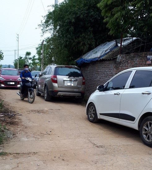 Nhiều ô tô đậu trên một con đường nhỏ trong làng ở Hòa Lạc, nơi xảy ra đợt sốt đất giữa dịch Covid-19.
