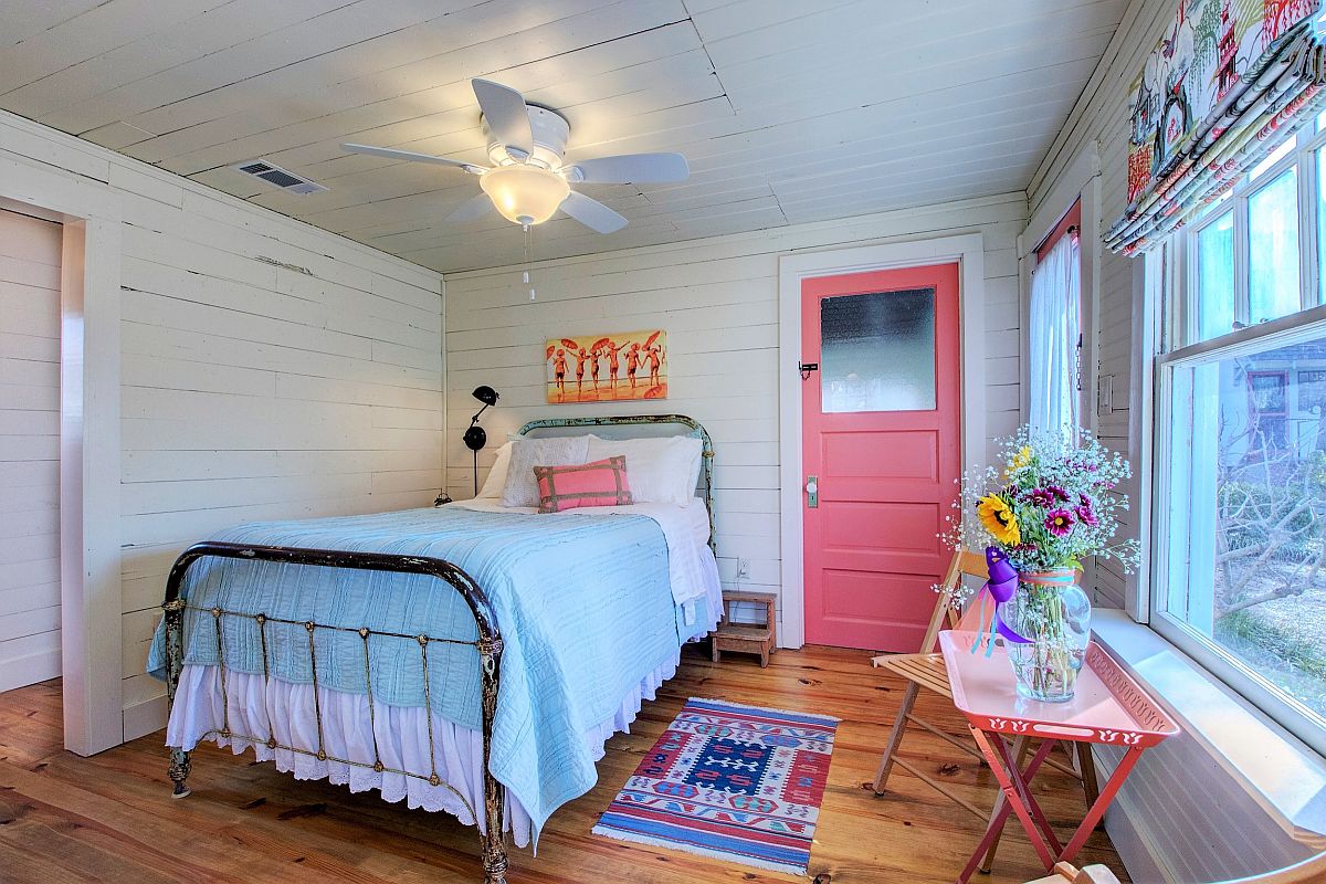 Hình ảnh phòng ngủ nhỏ sử dụng tông màu pastel chủ đạo với tường trần màu trắng, cửa màu hồng, ga xanh nhạt