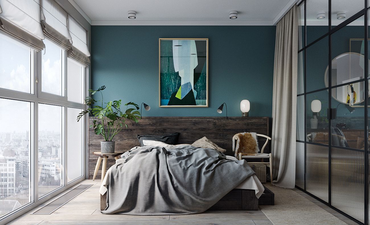 Hình ảnh toàn cảnh phòng ngủ trong căn hộ nhỏ với tường đầu giường sơn xanh dương, một phần ốp gỗ, treo tranh nghệ thuật trừu tượng