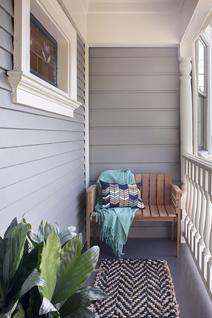 Hình ảnh hiên đẹp với ghế tựa gỗ, gối ôm màu sắc, chăn mỏng màu xanh và thảm trải cùng tông