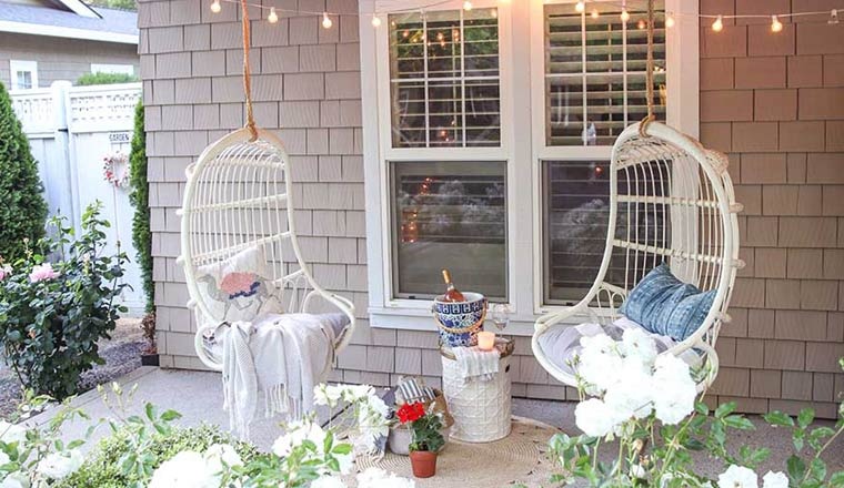 Hình ảnh hiên nhà với hai ghế xích đu, phía trên trang trí bằng đèn LED, xung quanh trồng hoa, cây cảnh