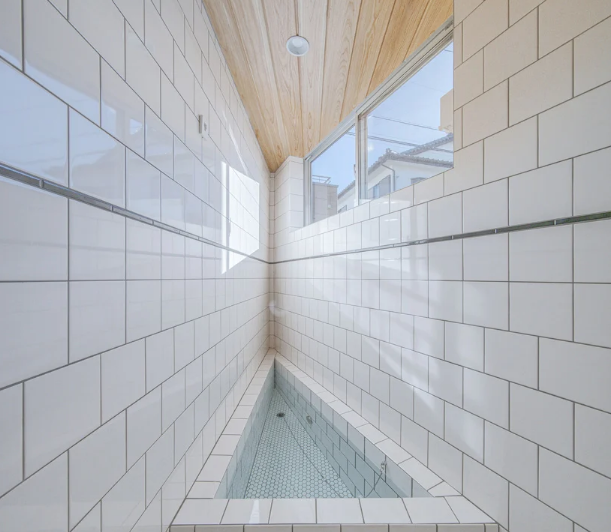 hình ảnh góc phòng tắm hình tam giác với trần gỗ và gạch ốp màu trắng sạch sẽ.