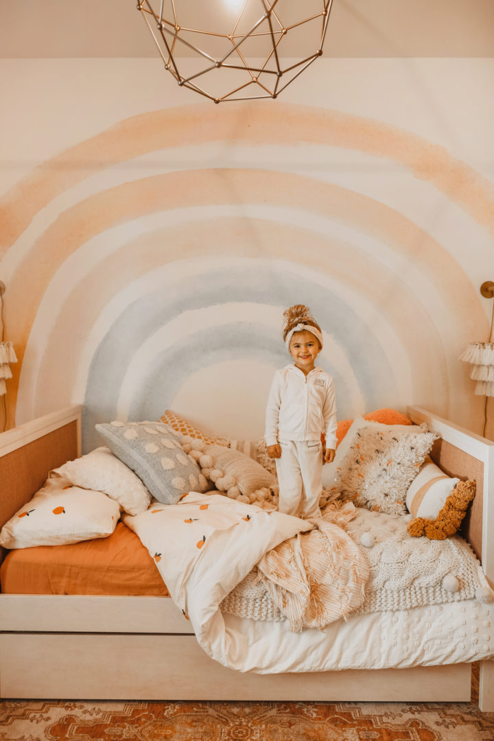 Hình ảnh một bé gái đang đứng chơi trên giường nệm êm ái