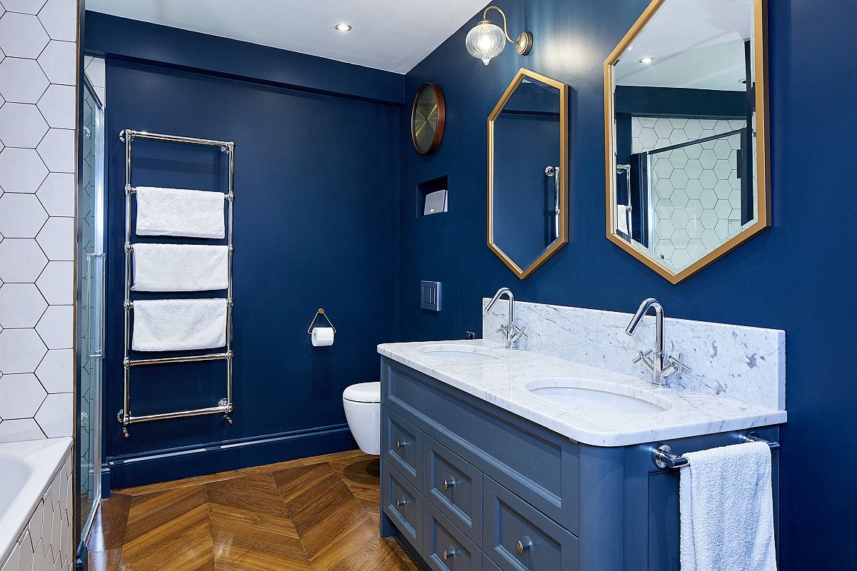 phòng tắm nhỏ với tường sơn xanh đậm, ốp gạch trắng, khung gương lục giác mạ đồng, thang lưu trữ gắn tường