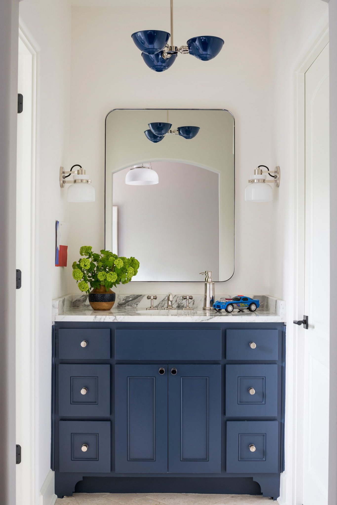 Hình ảnh phòng tắm nhỏ màu trắng chủ đạo, tủ đồ dưới bồn rửa màu xanh nổi bật