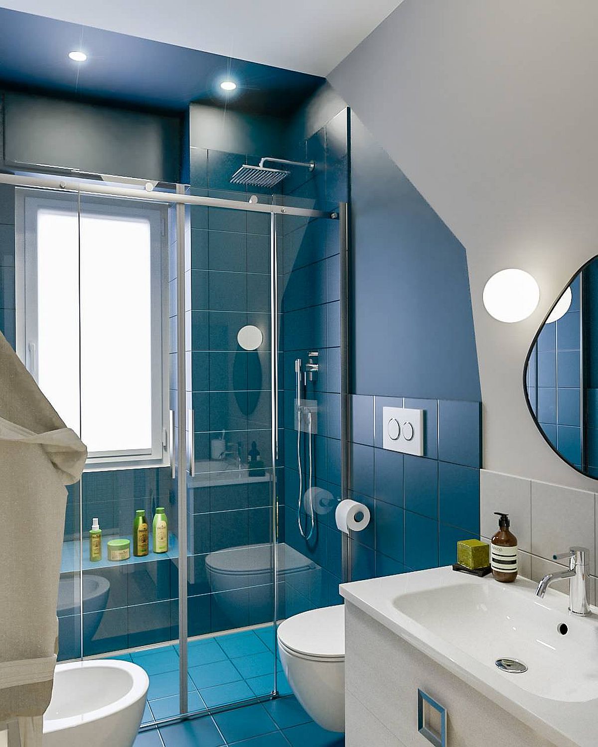 Hình ảnh phòng tắm nhỏ với buồng tắm đứng ốp gạch màu xanh, vách kính, bên ngoài là khu vực vệ sinh, đèn LED âm trần