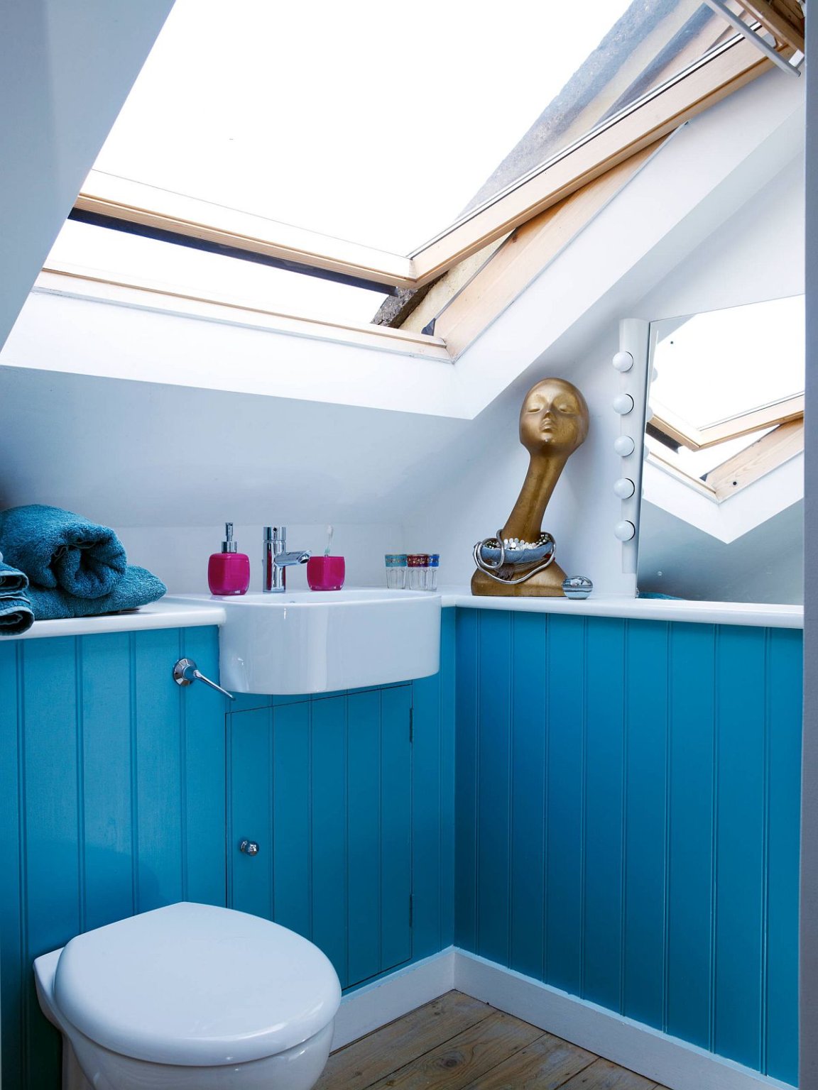Hình ảnh phòng tắm gác mái với mảng tường sơn xanh da trời, cửa sổ mái
