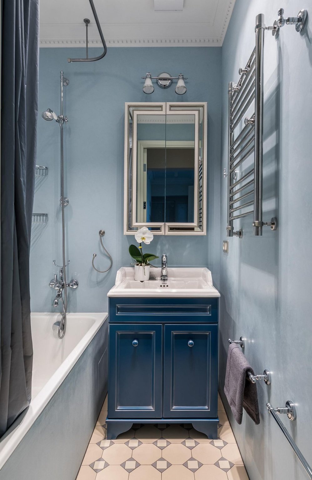 hình ảnh phòng tắm nhỏ với tường và rèm màu xanh nhạt, gạch lát họa tiết hình học