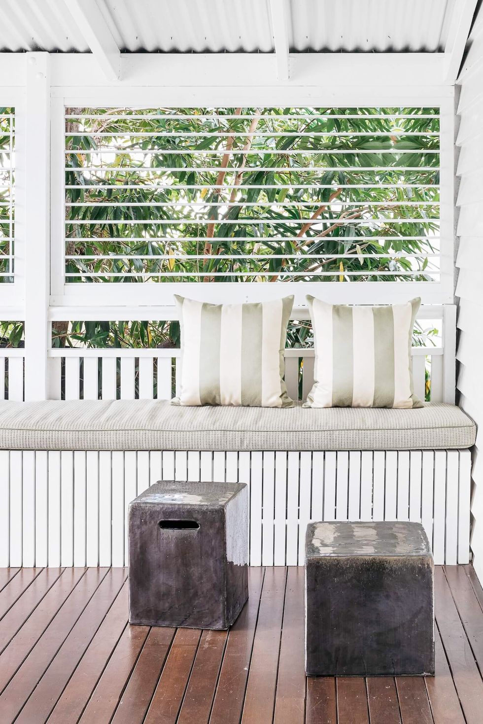 hình ảnh hiên nhà phía sau với mái thép mạ kẽm sơn trắng, băng ghế ngồi bọc nệm êm ái, sàn gỗ sẫm màu