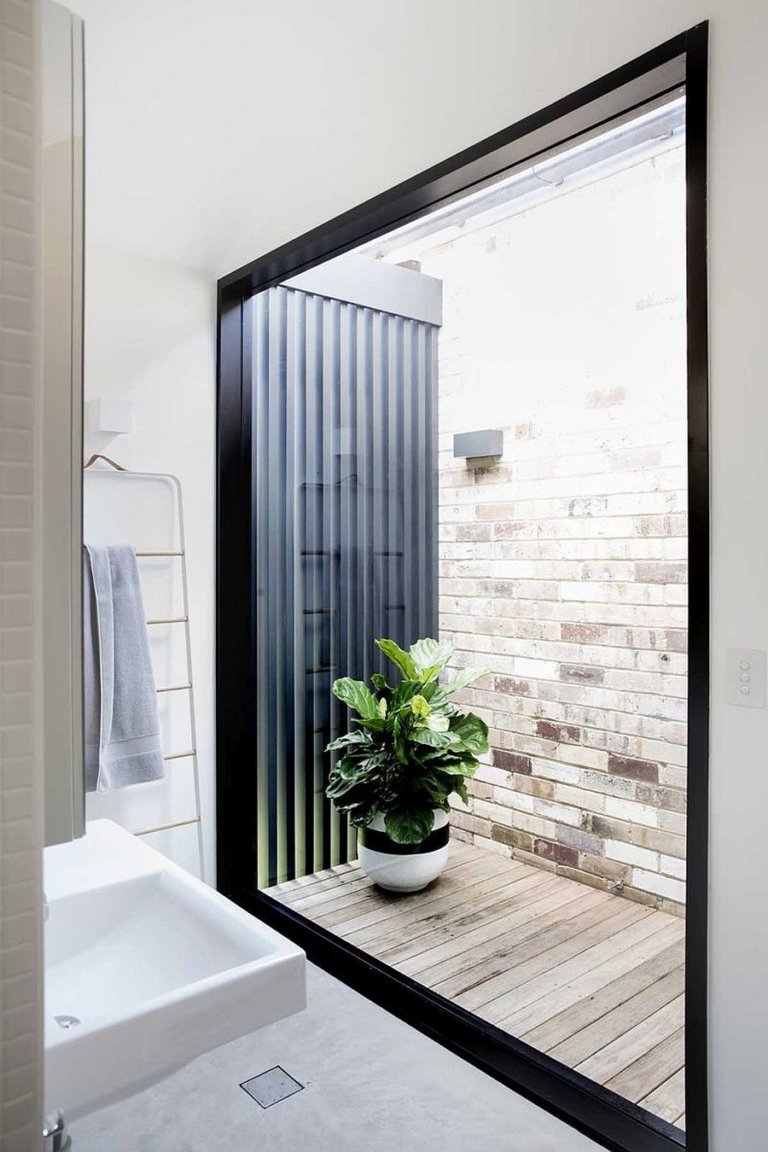 hình ảnh một góc phòng tắm có cửa sổ kính lớn mở ra khoảng sân nhỏ trồng cây xanh