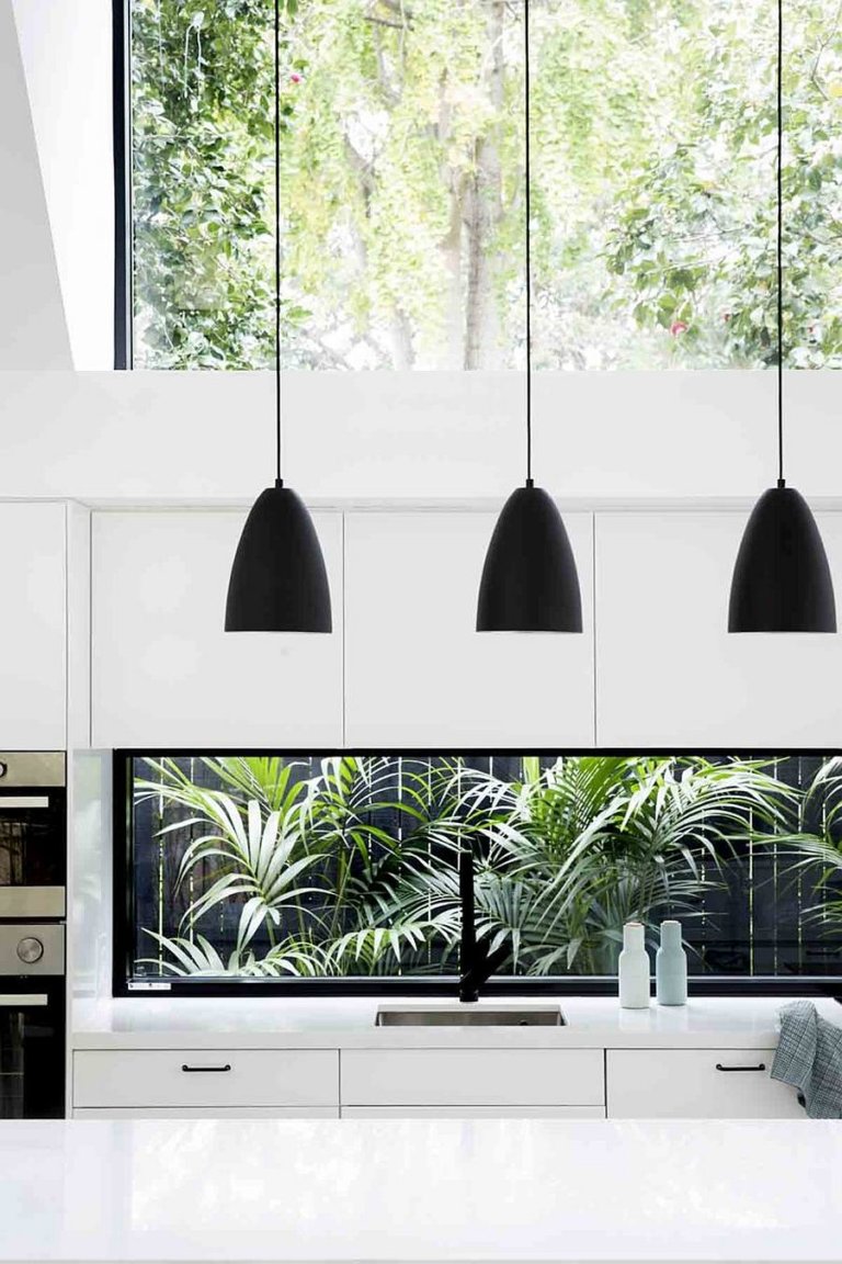 hình ảnh một góc phòng bếp hiện đại với đèn thả trần màu đen, tủ bếp trắng, cửa sổ kính lớn