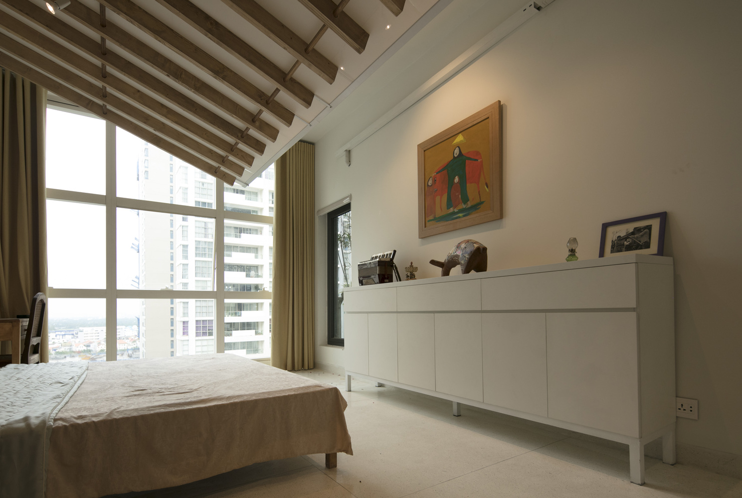 hình ảnh phòng ngủ hiện đại, thoáng sáng với tủ kệ lưu trữ màu trắng, cửa sổ kính lớn, dầm gỗ lộ thiên