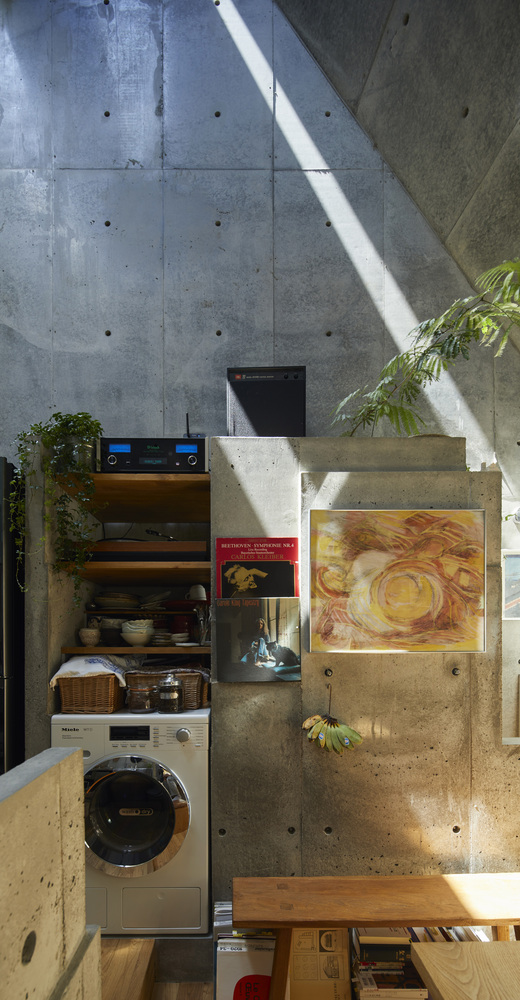 hình ảnh một góc phòng bếp với giá kệ gỗ gắn tường, máy giặt, bàn ghế gỗ