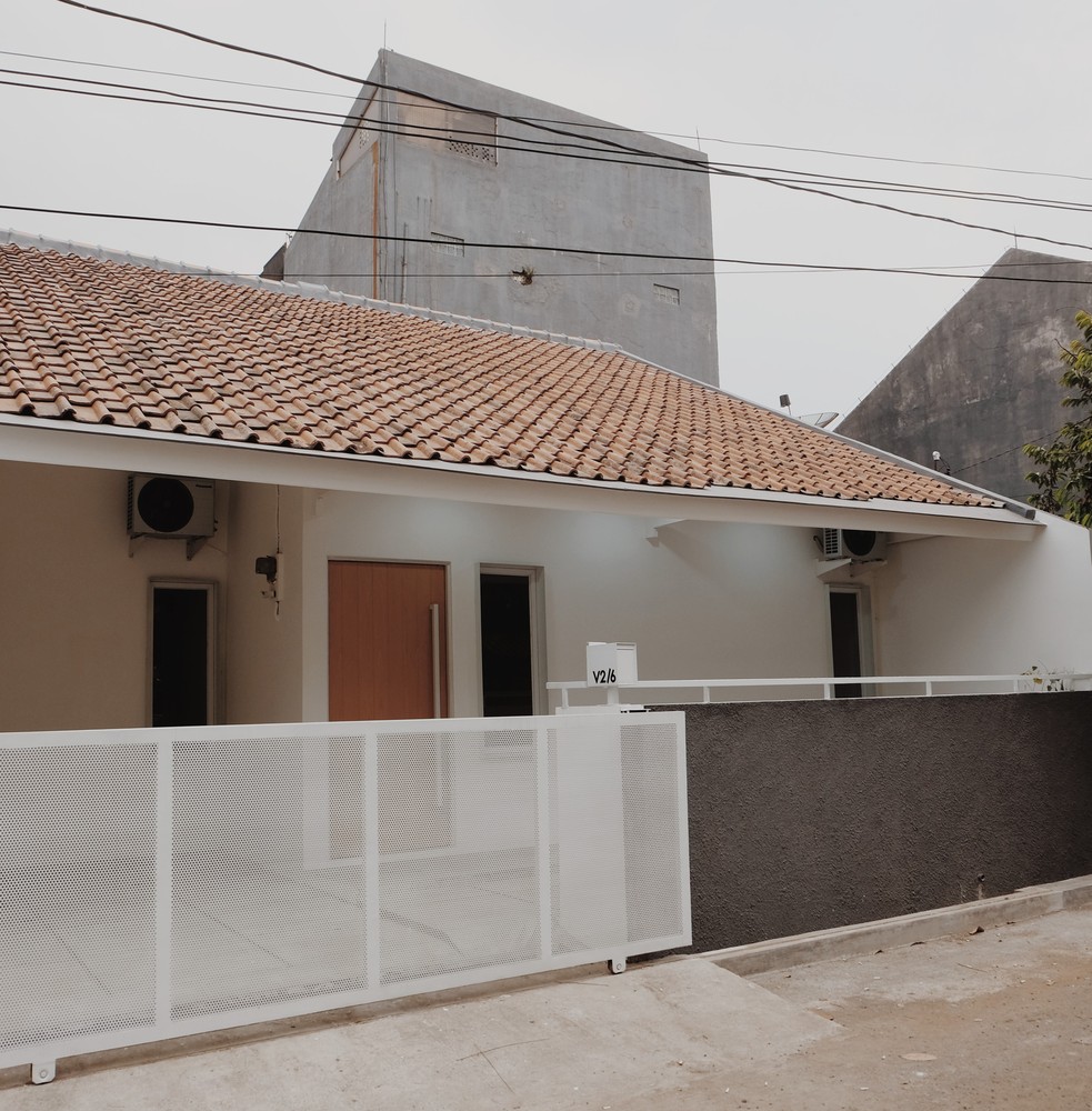 hình ảnh toàn cảnh mặt tiền ngôi nhà 76m2 ở Indonesia sau khi cải tạo với mái tôn lượn sóng, hàng rào kim loại sơn trắng
