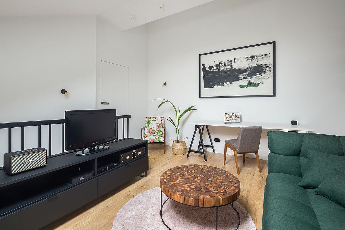 hình ảnh không gian phòng khách căn hộ 52m2 được bài trí gọn gàng, sang trọng với ghế sofa màu xanh lá đậm, bàn trà gỗ độc đáo, đối diện là tủ kệ tivi màu đen cá tính.