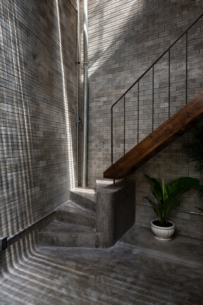 hình ảnh chân cầu thang trong ngôi nhà phong cách Zen với tường và sàn bê tông xám, cây xanh trang trí