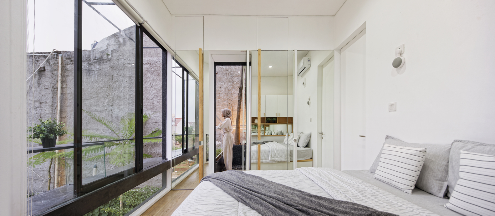 hình ảnh toàn cảnh phòng ngủ trên tầng 2 ngôi nhà với tường sơn trắng, gương soi, tường kính