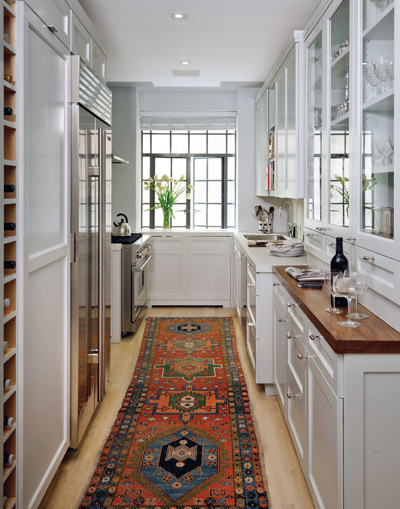 hình ảnh phòng bếp phong cách Art Deco với hệ tủ bếp màu trắng cao kịch trần, thảm trải thổ cẩm màu rực rỡ