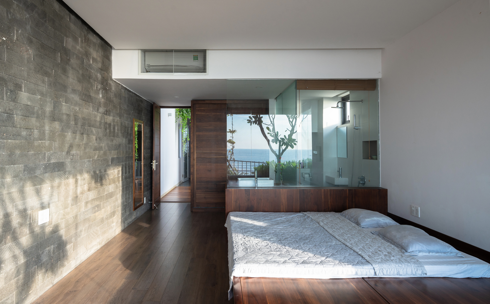 hình ảnh phòng ngủ rộng rãi, bài trí tối giản với nội thất gỗ, cửa kính trong suốt