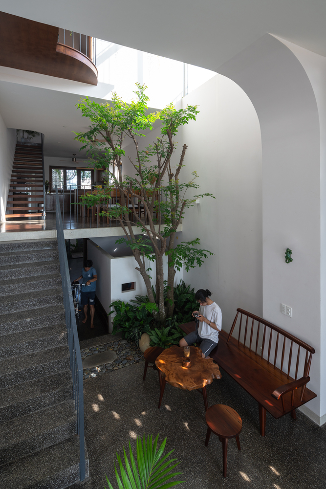 hình ảnh khoảng thông tầng trung tâm trồng cây xanh của nhà ven biển với cầu thang bậc hở, bàn ghế thư giãn