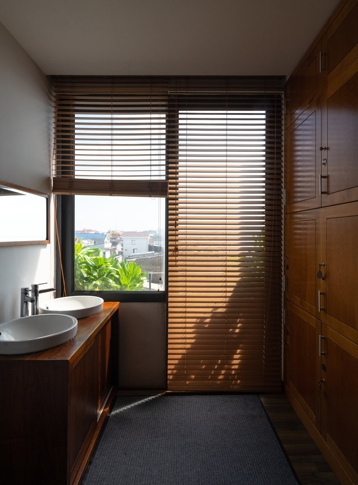 hình ảnh bên trong phòng tắm hiện đại, thoáng sáng với bồn rửa đôi, cửa sổ kính, nội thất gỗ