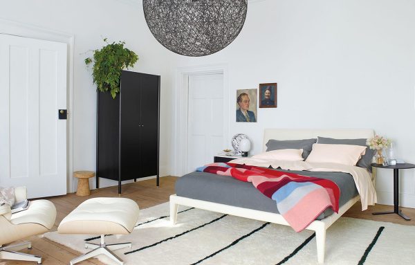 hình ảnh phòng ngủ tông màu trắng chủ đạo, sử dụng thảm trải sàn trắng kẻ sọc đen, chậu cây trang trí, đèn thả hình tròn xám lớn