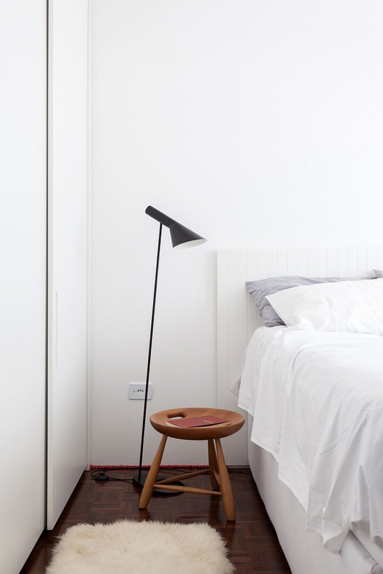 hình ảnh một góc phòng ngủ với giường nệm màu trắng, đèn sàn màu đen, ghế gỗ nhỏ