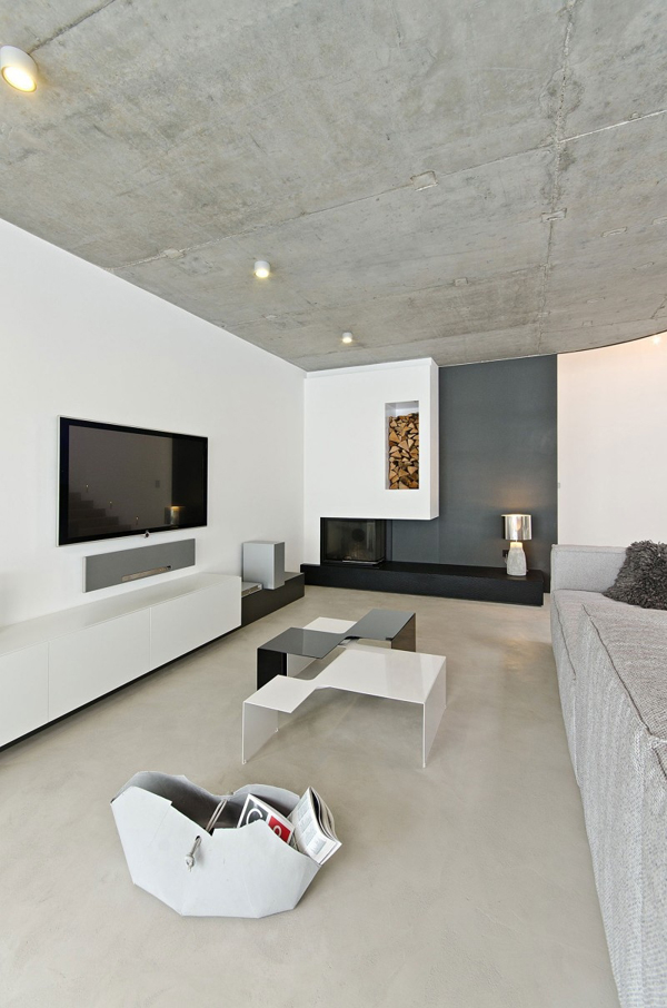 Hình ảnh phòng khách có thiết kế đơn giản với trần bê tông xám, sofa cùng tông màu, tủ kệ tivi, đèn trần ánh sáng vàng