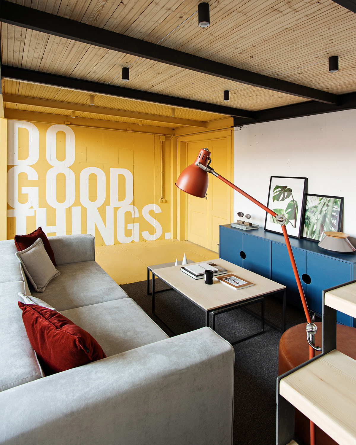 hình ảnh phòng họp nhóm với sofa ghi xám, bàn trà gỗ, tủ lưu trữ màu xanh, bức tường vàng điểm nhấn