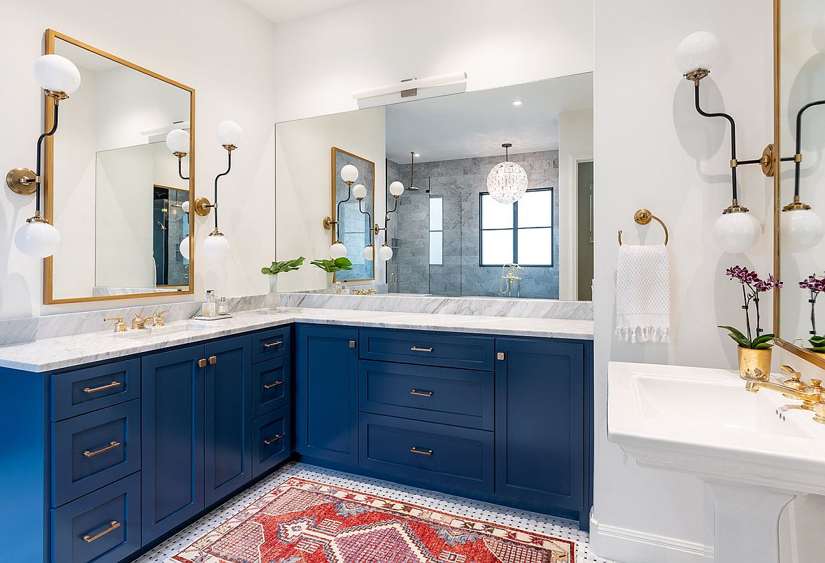 hình ảnh phòng tắm màu trắng chủ đạo, tủ màu xanh dương, khung gương, tay nắm ngăn kéo và chậu hoa mạ vàng sáng bóng