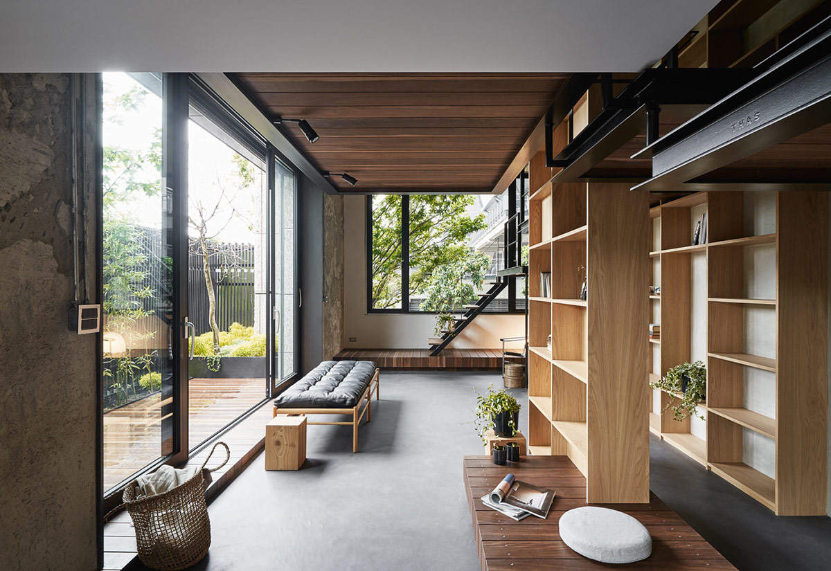 hình ảnh phòng khách ngôi nhà Nhật với băng ghế dài bọc da màu đen, cửa kính trong suốt, giá sách bằng gỗ