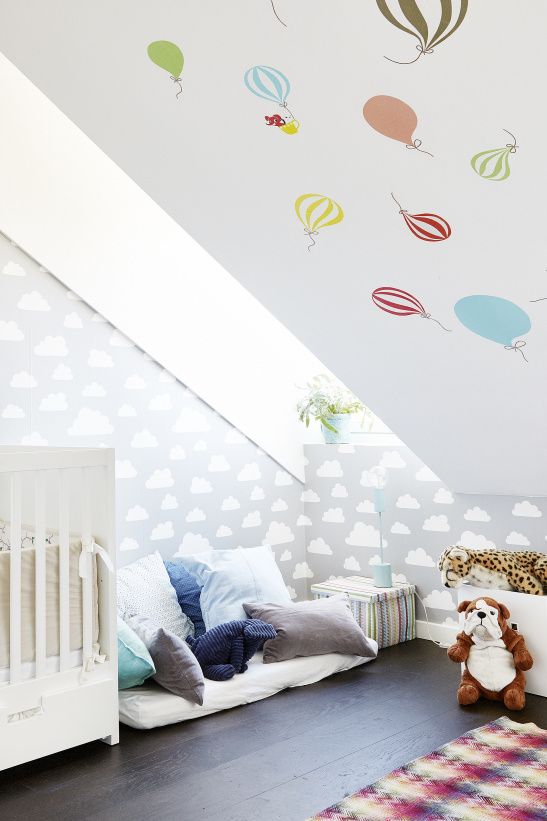 Phòng ngủ gác mái đáng yêu hơn bao giờ hết với những chiếc gối đầy màu sắc, một bức tường mây, trần nhà với những chiếc khinh khí cầu cho tâm hồn bay bổng và một số đồ chơi, món đồ nội thất họa tiết thổ cẩm