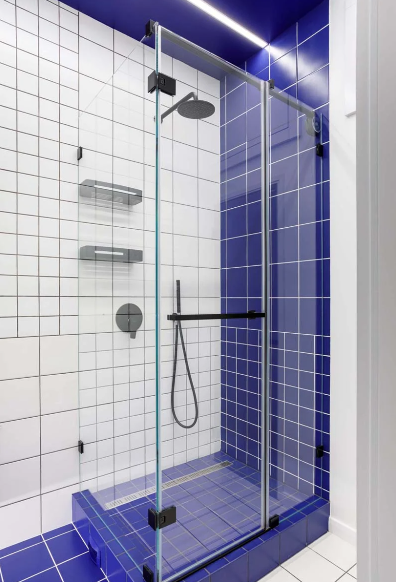 Phòng tắm cũng mang đến cái nhìn đồ họa đầy thu hút với những ô gạch trắng và được nhấn nhá bởi mảng màu xanh tím đậm chạy từ trần nhà xuống tường và sàn nhà
