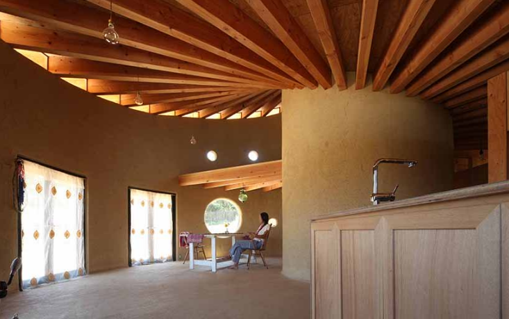 hình ảnh không gian bên trong ngôi nhà hình xoắn ốc với dầm gỗ tự nhiên, đèn sợi đốt