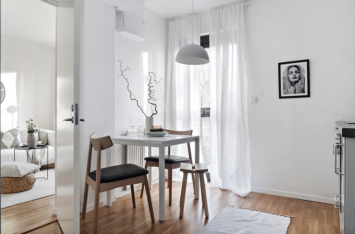hình ảnh phòng ăn nhỏ màu trắng với bàn gỗ có thể gấp gọn, đèn thả màu trắng, cành cây trang trí