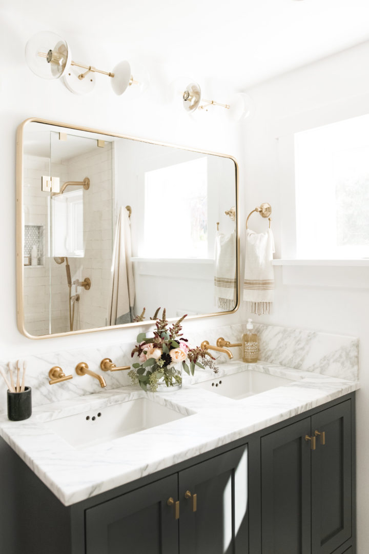 hình ảnh gương phòng tắm treo ở bức tường phía trên bồn rửa mặt, cạnh khung cửa sổ giúp hút sáng hiệu quả