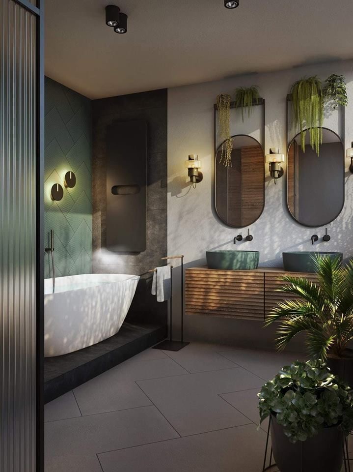 hình ảnh phòng tắm phong cách nhiệt đới với bồn tắm nắm đặt cạnh bức tường ốp gạch xanh, cạnh đó là bồn rửa mặt, phía trên treo gương hình bầu dục, cây xanh trang trí