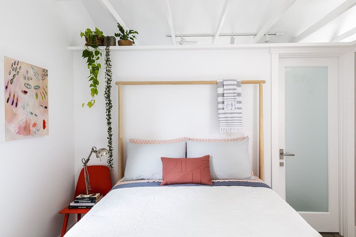 hình ảnh phòng ngủ nhỏ đẹp với giường nệm màu trắng, ghế đỏ đầu giường, cây xanh trang trí