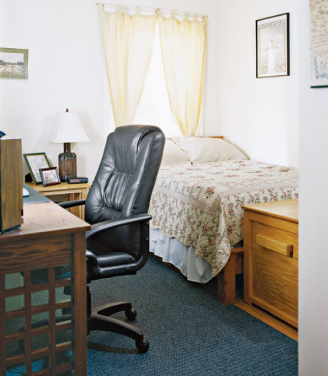 hình ảnh phòng ngủ nhỏ với cửa sổ đầu giường, bàn làm việc ngay cạnh, ghế da nặng nề