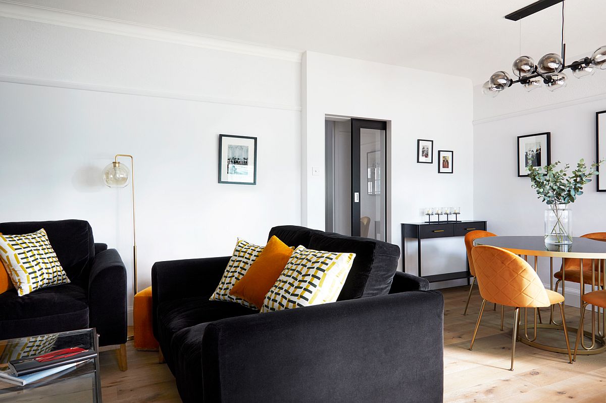 Phòng khách và phòng ăn căn hộ 2 phòng ngủ được thiết kế liên thông không tường ngăn với sofa màu đen, ghế ăn màu vàng