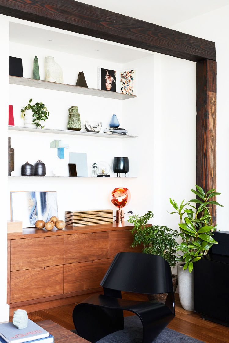 hình ảnh một góc phòng làm việc với bàn gỗ, ghế đen, kệ nổi gắn tường bày đồ trang trí